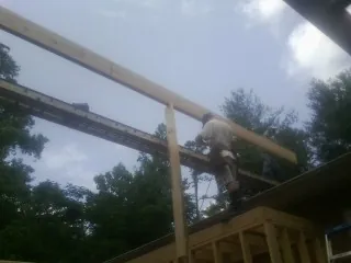 Carpenter setting a ridge beam over a new addition frame — Ice Dam Removal by Roofing Brothers in Sloan