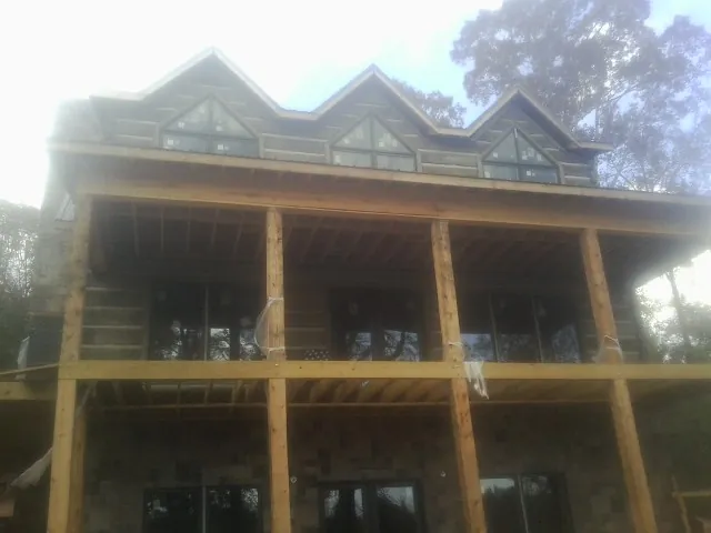 Dormers and porch framing on a large log home under construction — Roof Coating work by our crew in Sloan