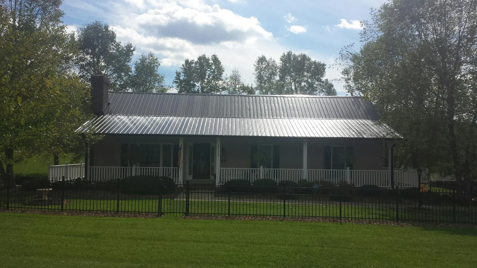 Gray metal roof on a brick ranch with a full width front porch — Gutter Guard Installation work by our crew in Sloan