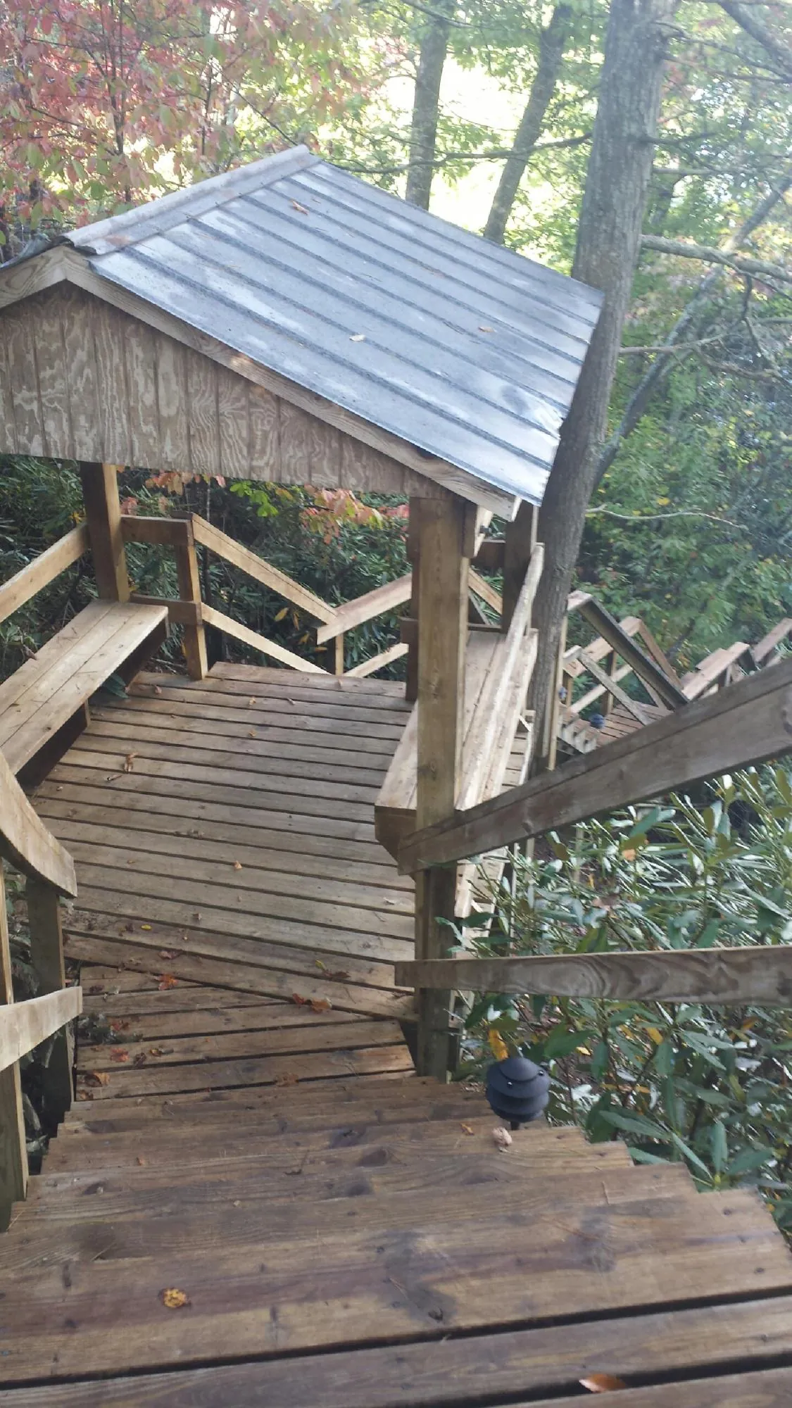 Metal roofed shelter over wooden steps on a wooded walkway — Skylight Repair & Installation work by our crew in Sloan