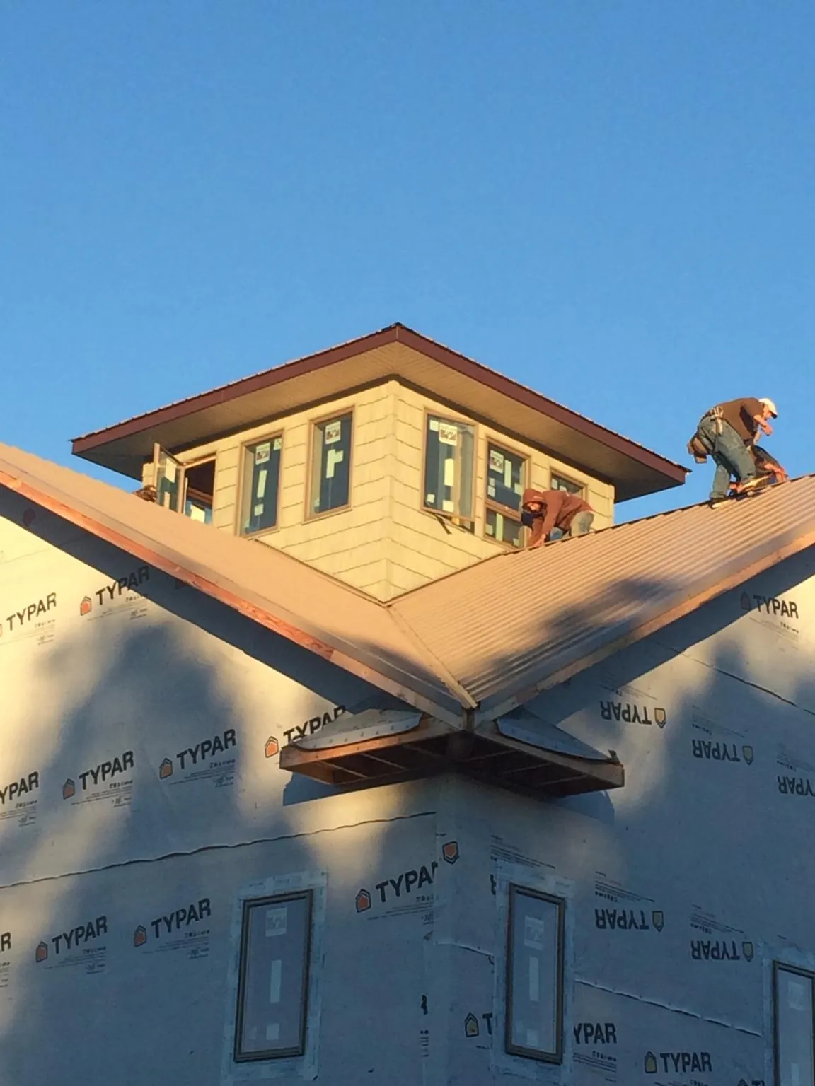 Roofers working around a rooftop cupola on a new metal roof at sunset — Roof Waterproofing in Sloan by Roofing Brothers